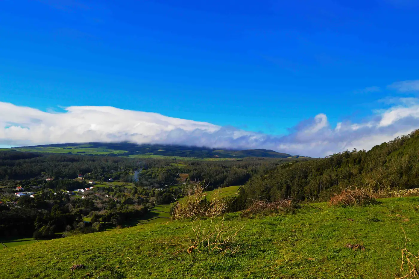Pastagens e matas do interior da ilha com nuvens baixas sobre a serra